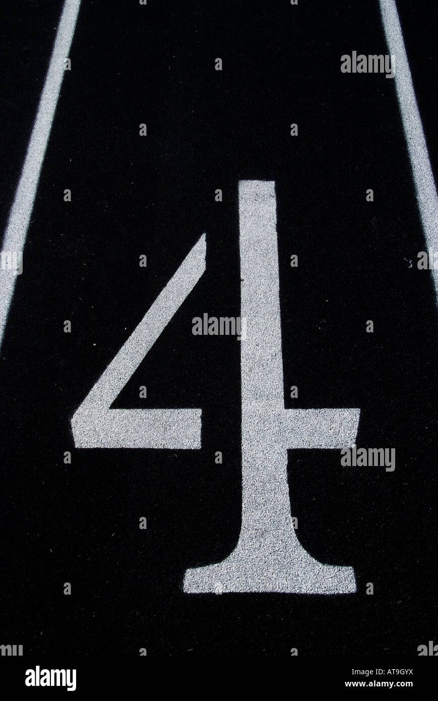 White number four on the black surface of an athletic running track. Stock Photo