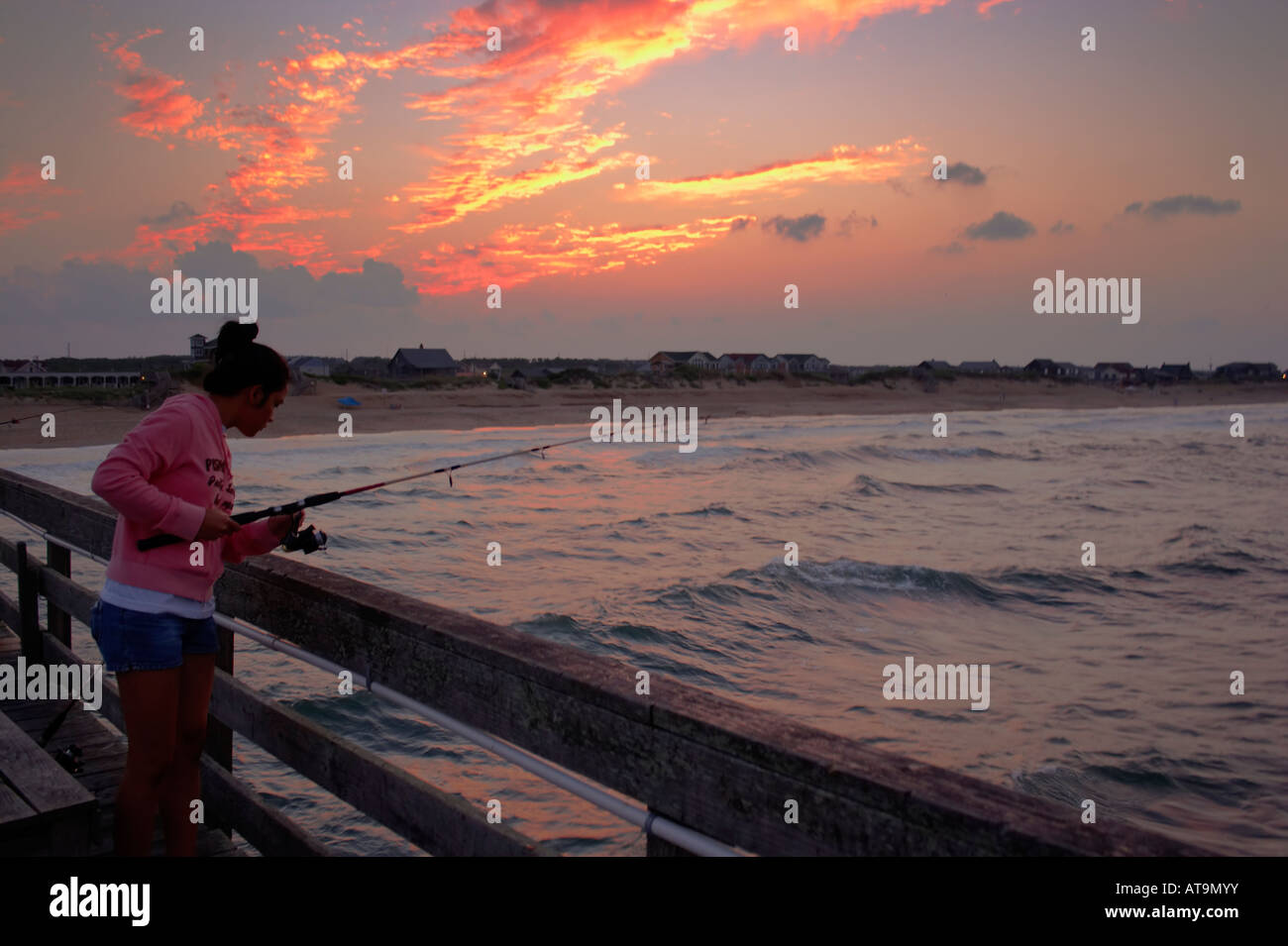 A girl fishing off the Nags Head Pier at sunset Nags Head North Carolina Stock Photo Alamy