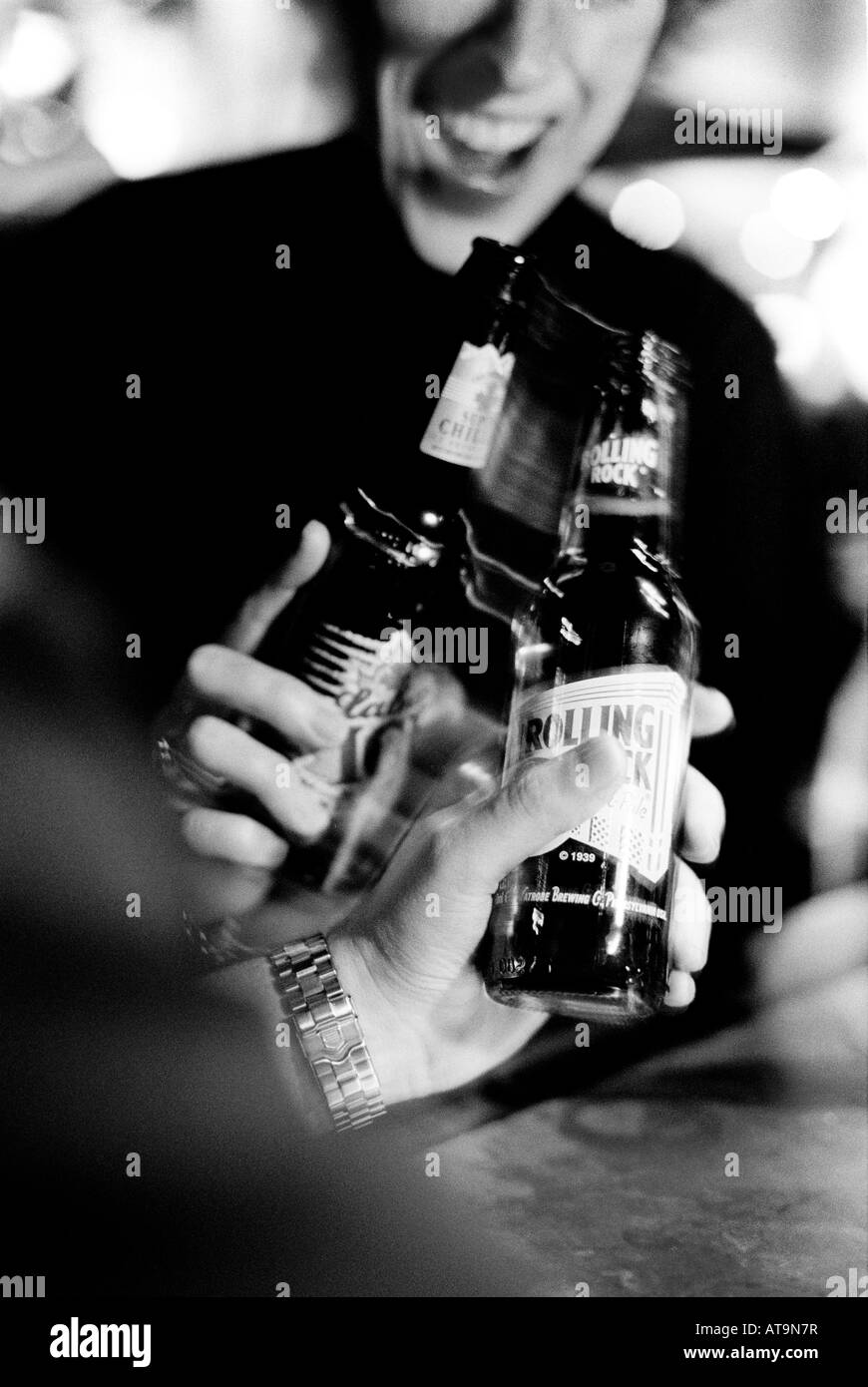 Friends toasting with clinking beer bottles in a London bar Stock Photo