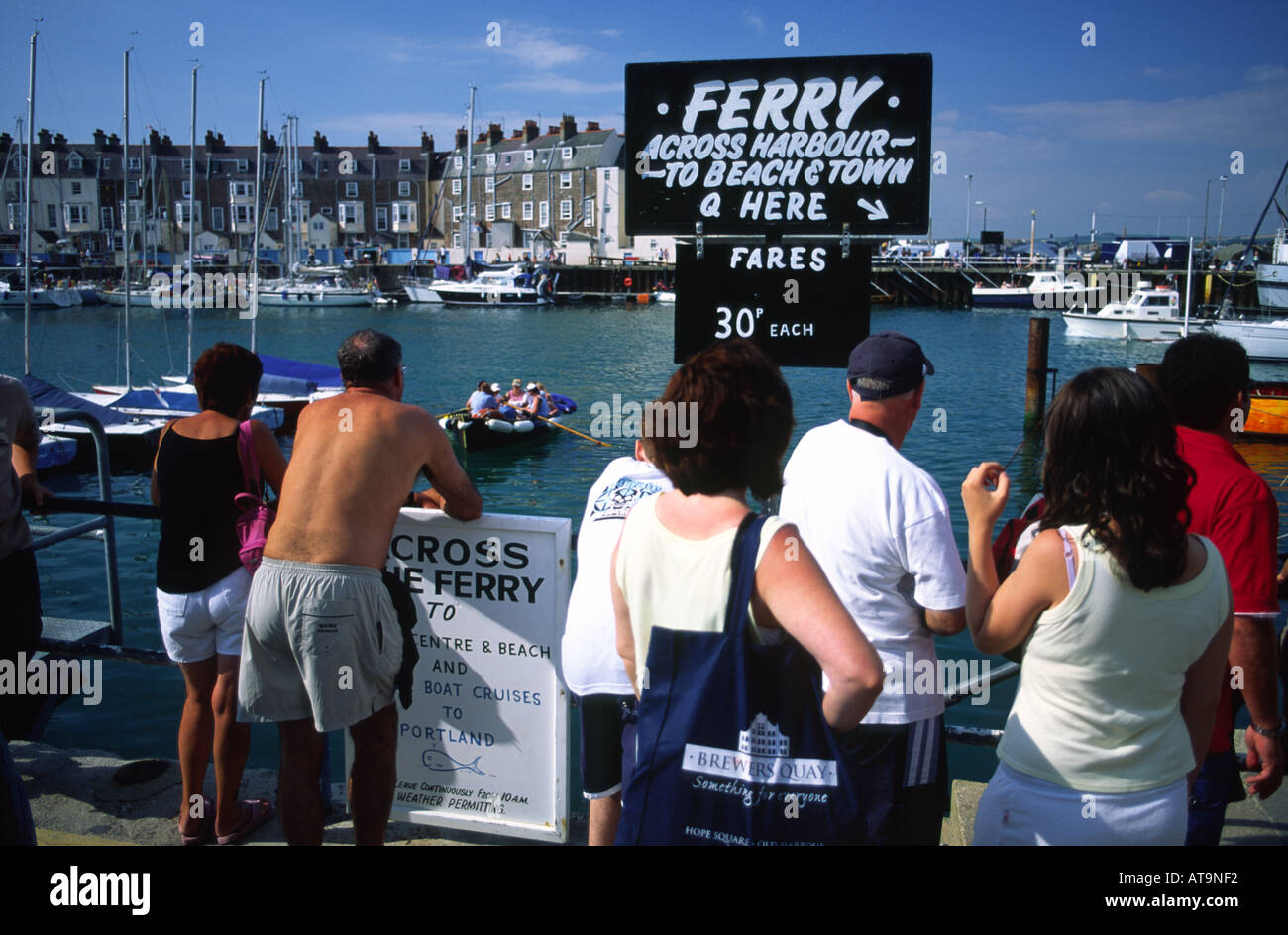 People queuing for the ferry across Weymouth harbour on a hot summer day Dorset county England UK Stock Photo