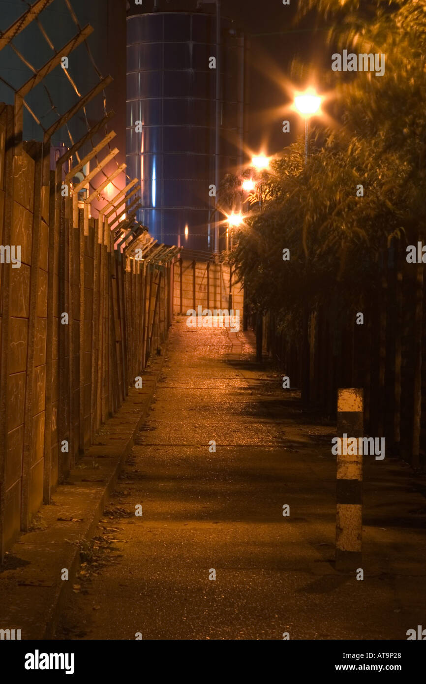 Dark and dangerous looking alley at night leading to industrial plant