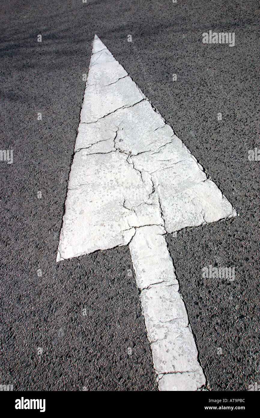 White arrow on road indicating direction for traffic to follow Stock Photo