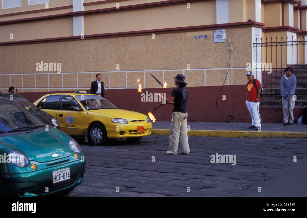 Young man juggling with sticks of fire on the red light traffic lights