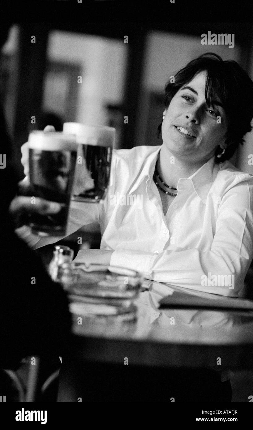 Woman clinking beer glasses with companion in a  Bar, Prague. Czech Republic 2001 Stock Photo
