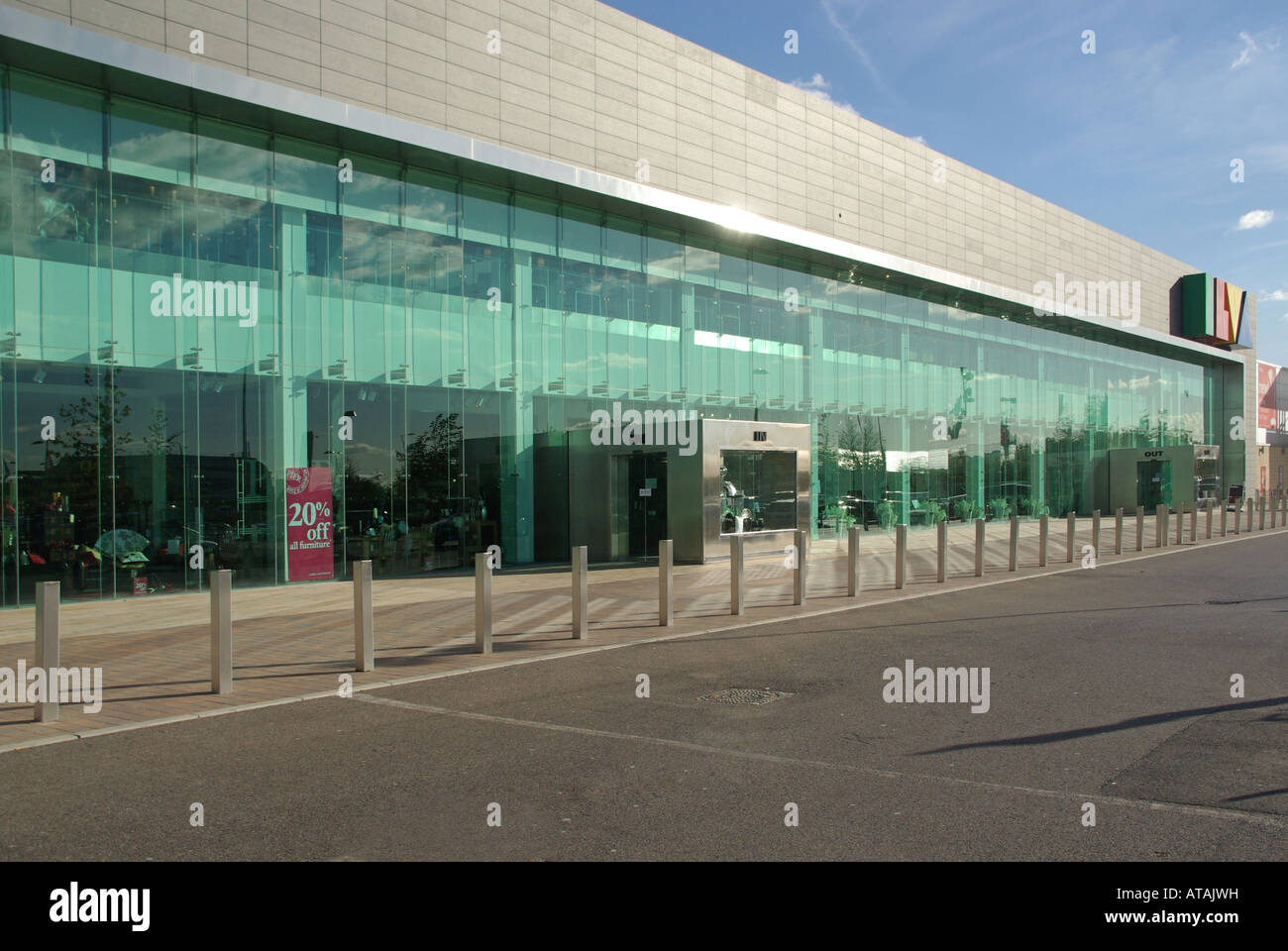 Very long glass frontage ilva furniture store with car parking and anti ram raid security bollards along shop front pavement Lakeside Essex England UK Stock Photo