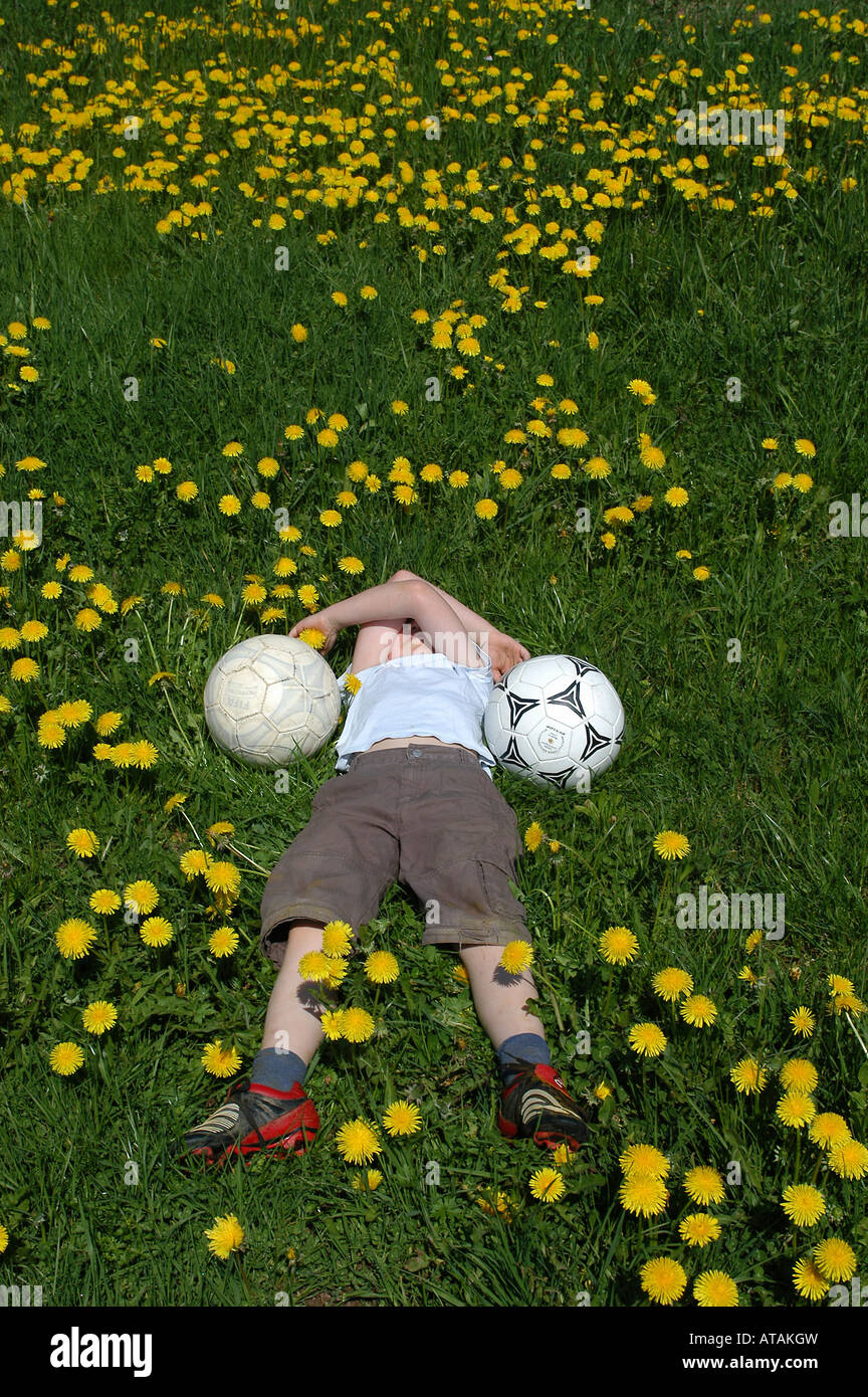 Young boy and footballs, lying on a meadow Stock Photo