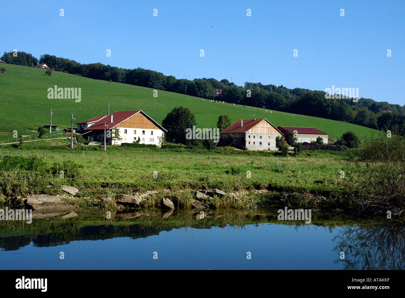 Traditional comtois farmhouses in France's Jura region on the banks of the Doubs river where it faces Switzerland Stock Photo