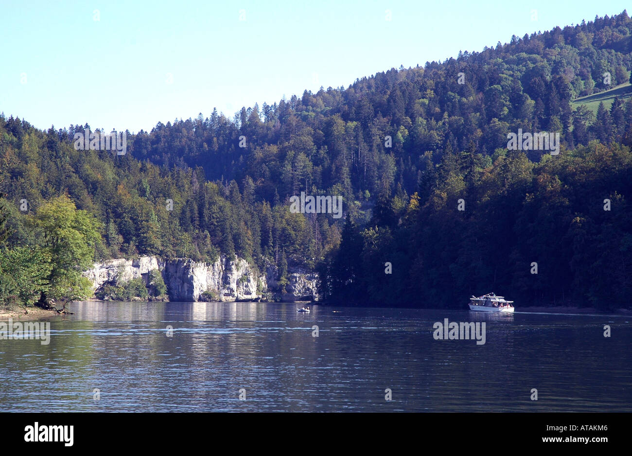 Pleasure boats cruise towards a waterfall along the Doubs river between France and Switzerland Stock Photo
