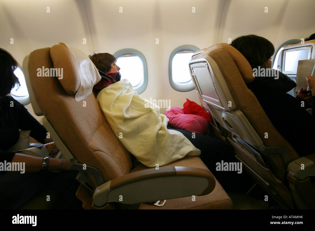 A woman passenger sleeping in a reclined seat  on a long haul flight; Etihad Airline Stock Photo
