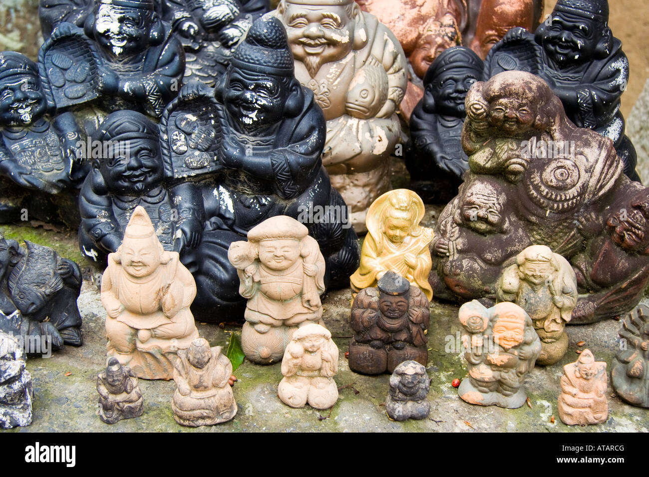 Small statues of the Shichifukujin, seven Japanese gods of happiness and good fortune arranged on the ground at the Achi-jinja shrine at Kurashiki. Stock Photo