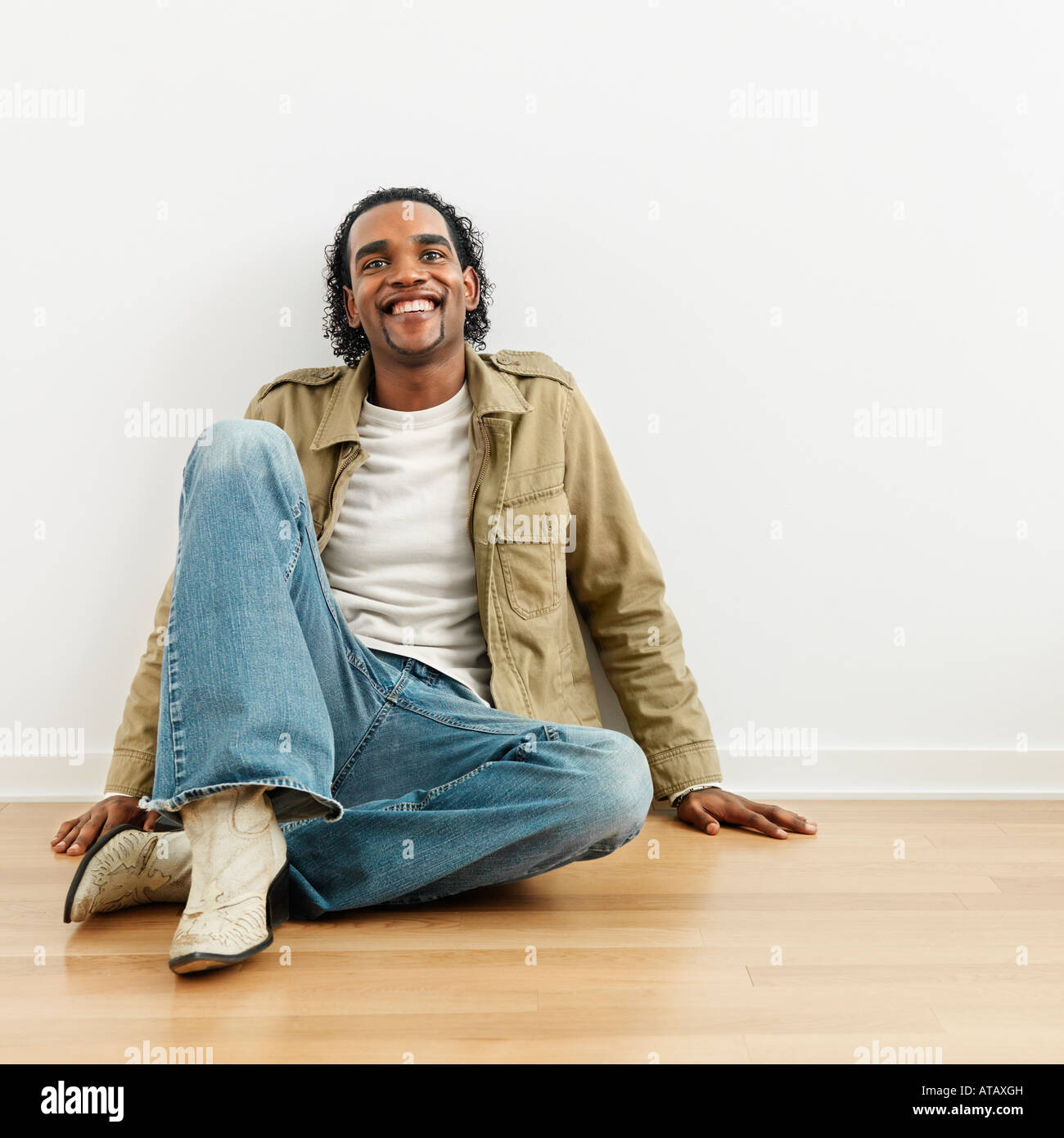 Man sitting on wood floor of home smiling Stock Photo - Alamy