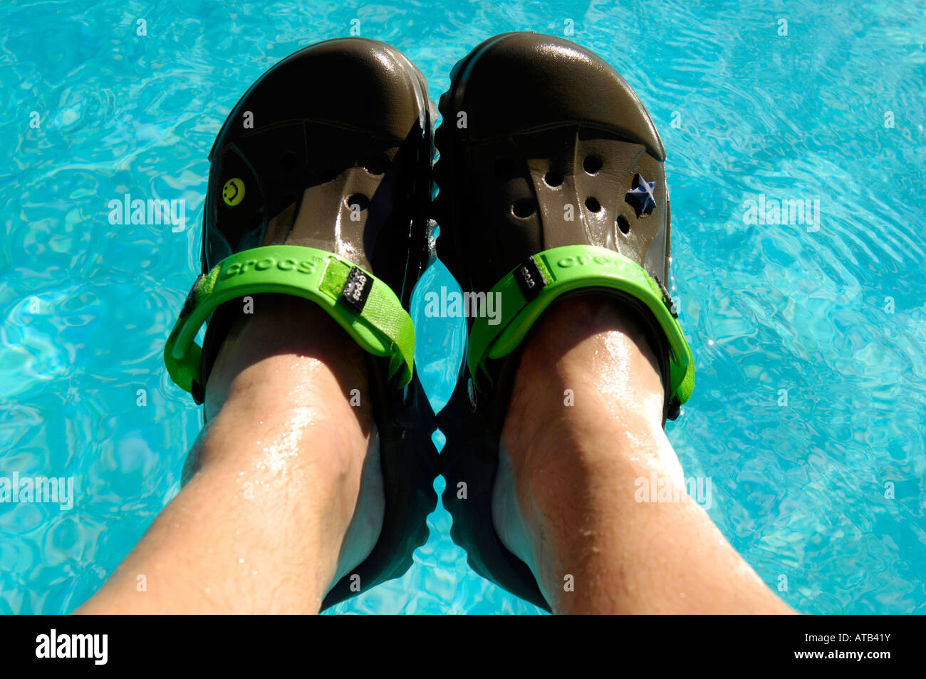 crocs chocolate lime offroad footwear swimming pool floating shoes holiday vacation blue colour horizontal legs rest relax Stock Photo