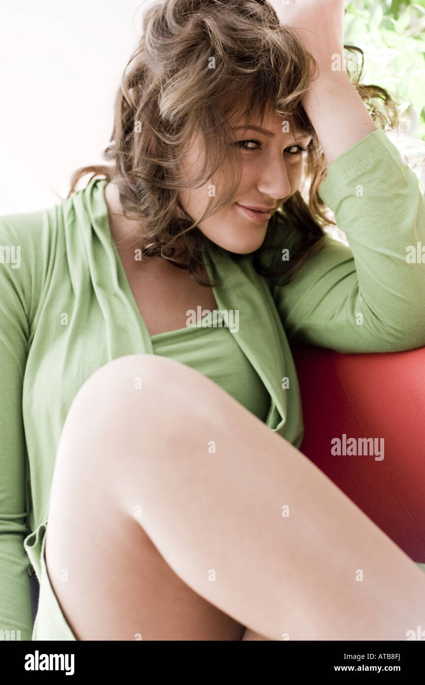 young woman in green dress stting in a armchair Stock Photo