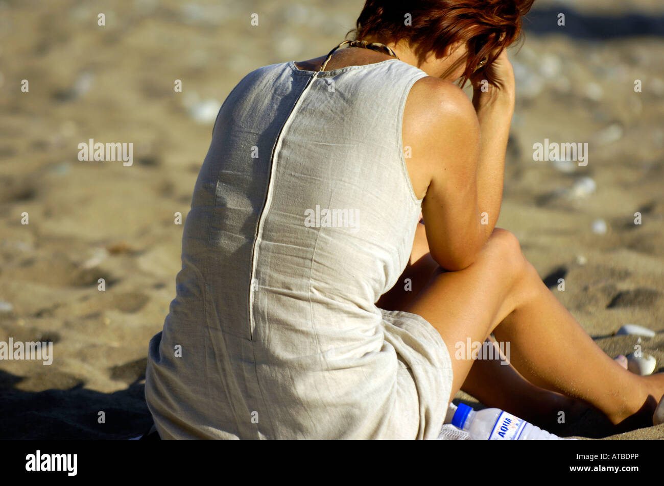 redhead woman relaxing on beach sitting Stock Photo
