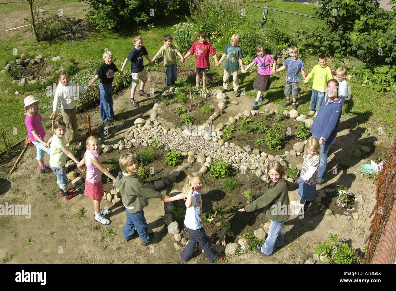 class of a primary school with their teacher in front of their flower bed designed like a butterfly Stock Photo