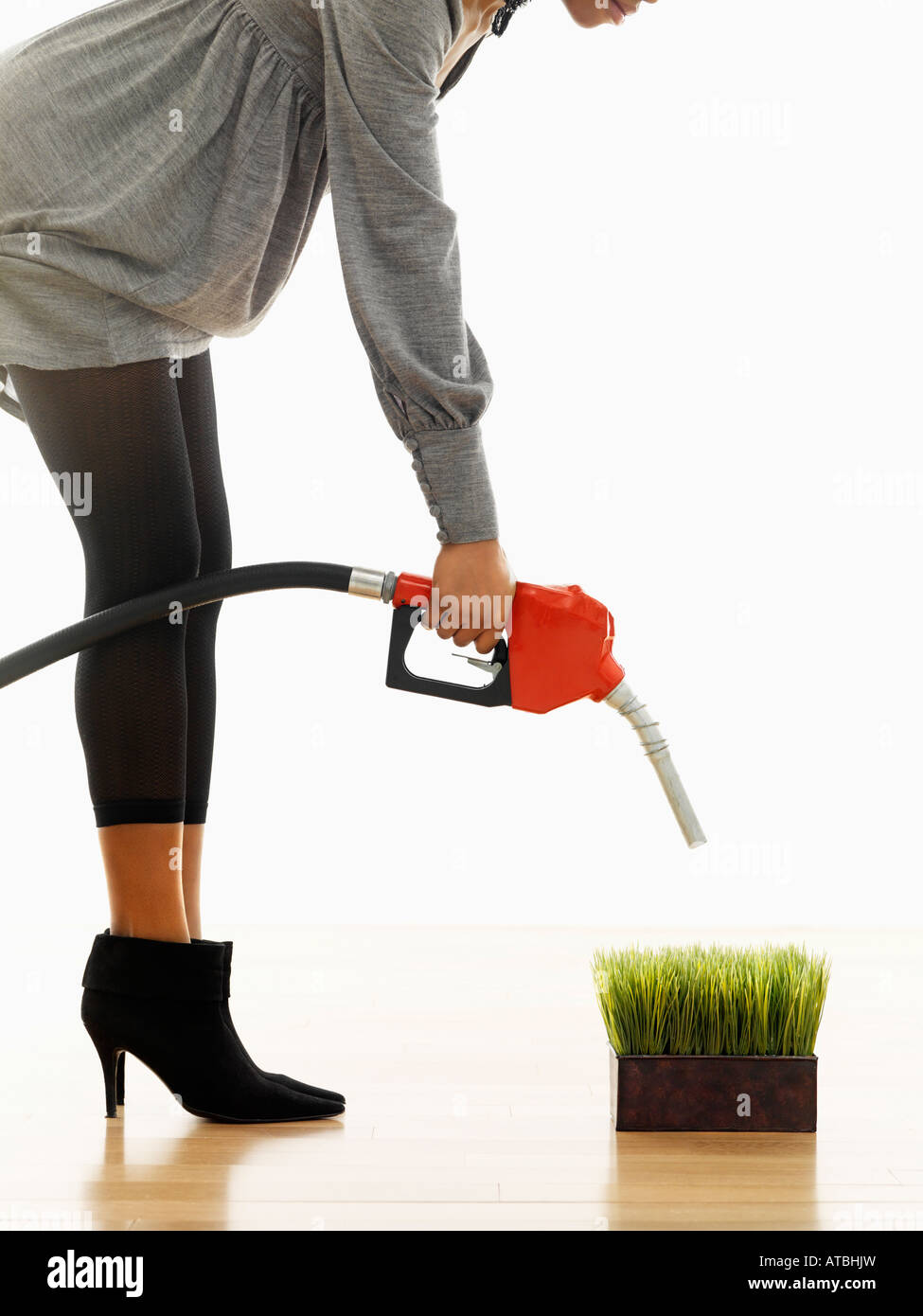 Woman holding gasoline pump nozzle over green grass Stock Photo