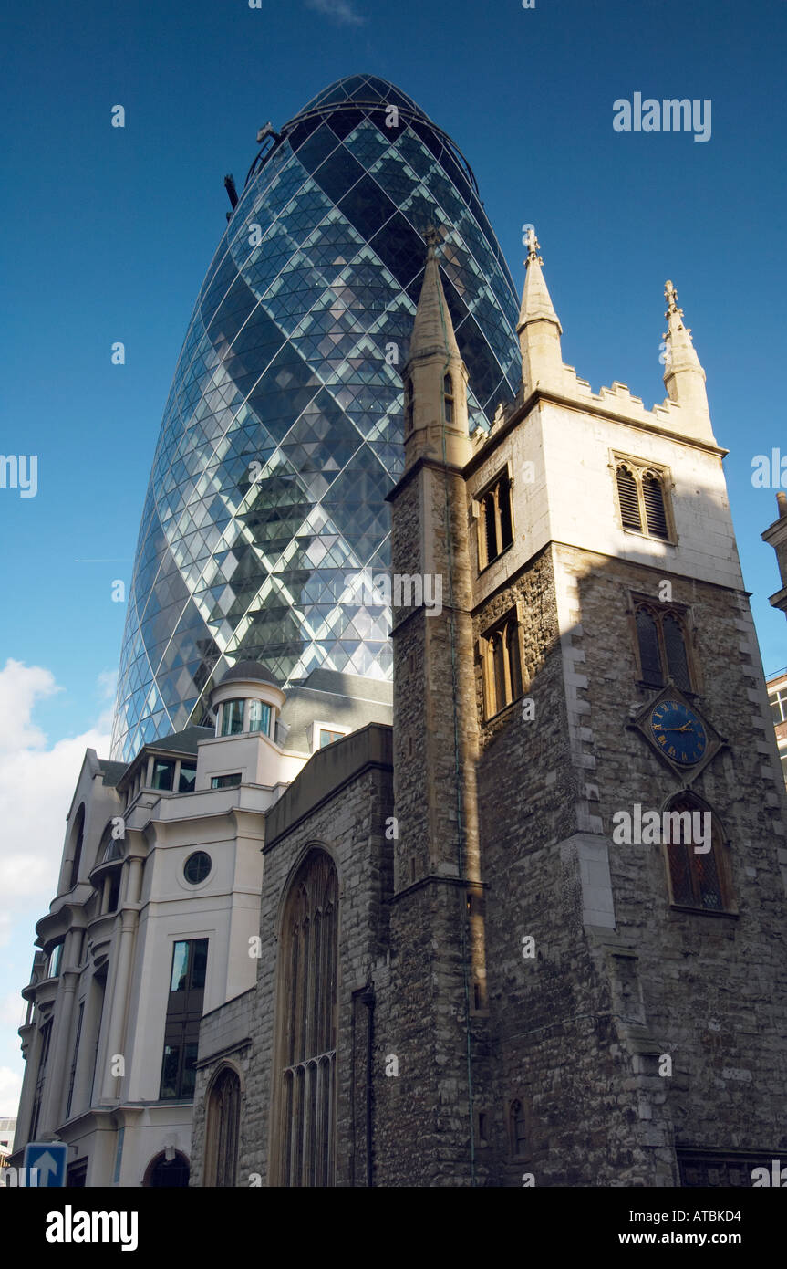 st mary axe with the Swiss Re (gerkin} behind it against a blue sky  showing the city's old and new styles of Architecture Stock Photo
