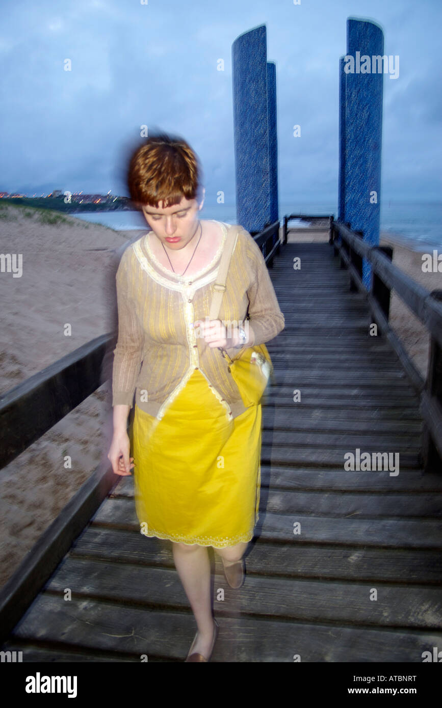 girl going for a walk for in wooden promenade next to suances beach at the evening Stock Photo