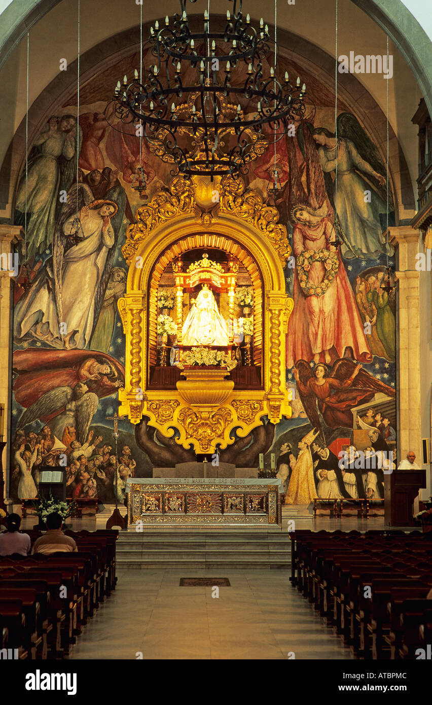 The interior of the Basilica of Nuestra Senora de la Candelaria showing the richly dressed statue of the Madonna above the altar with a background of frescoes Stock Photo