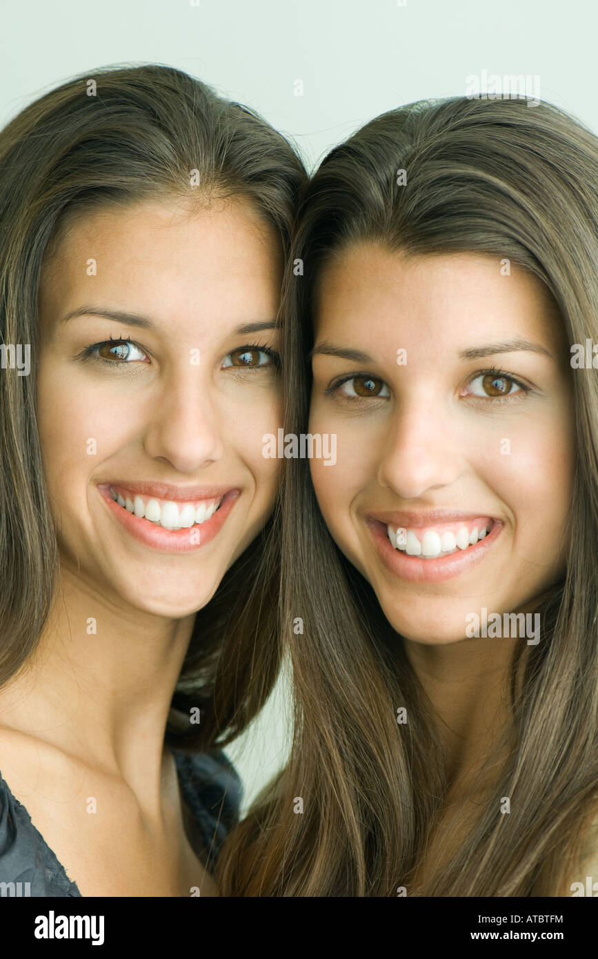 Two twin teenage sisters smiling at camera, cheek to cheek, portrait Stock Photo