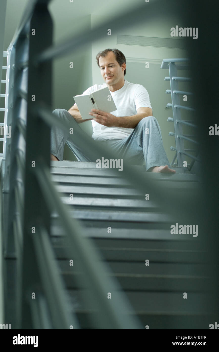 Man sitting at top of staircase reading book, selective focus Stock Photo