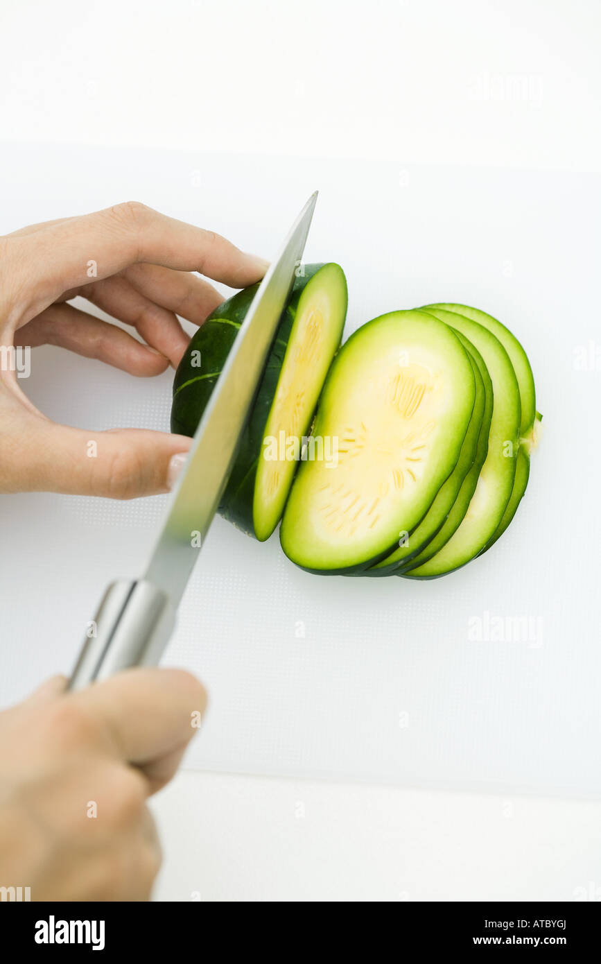Hands cutting summer squash (zapallito redondo), with knife, cropped