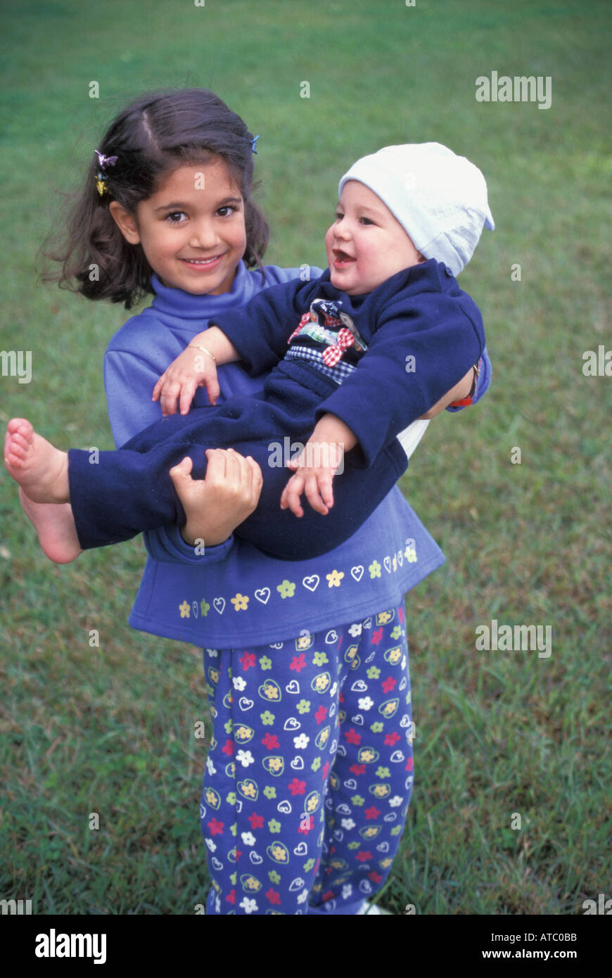 5 y o Tahitian girl proudly holds her baby brother MR available Stock Photo