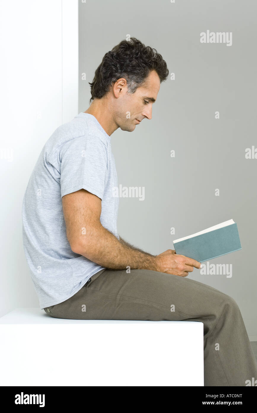Man sitting, reading book, side view Stock Photo