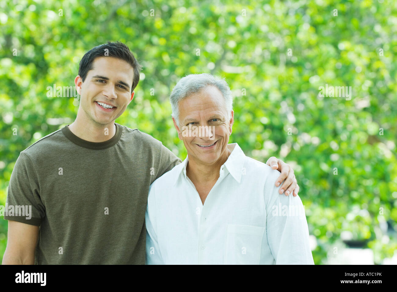 Mature man and adult son smiling at camera together outdoors, portrait Stock Photo