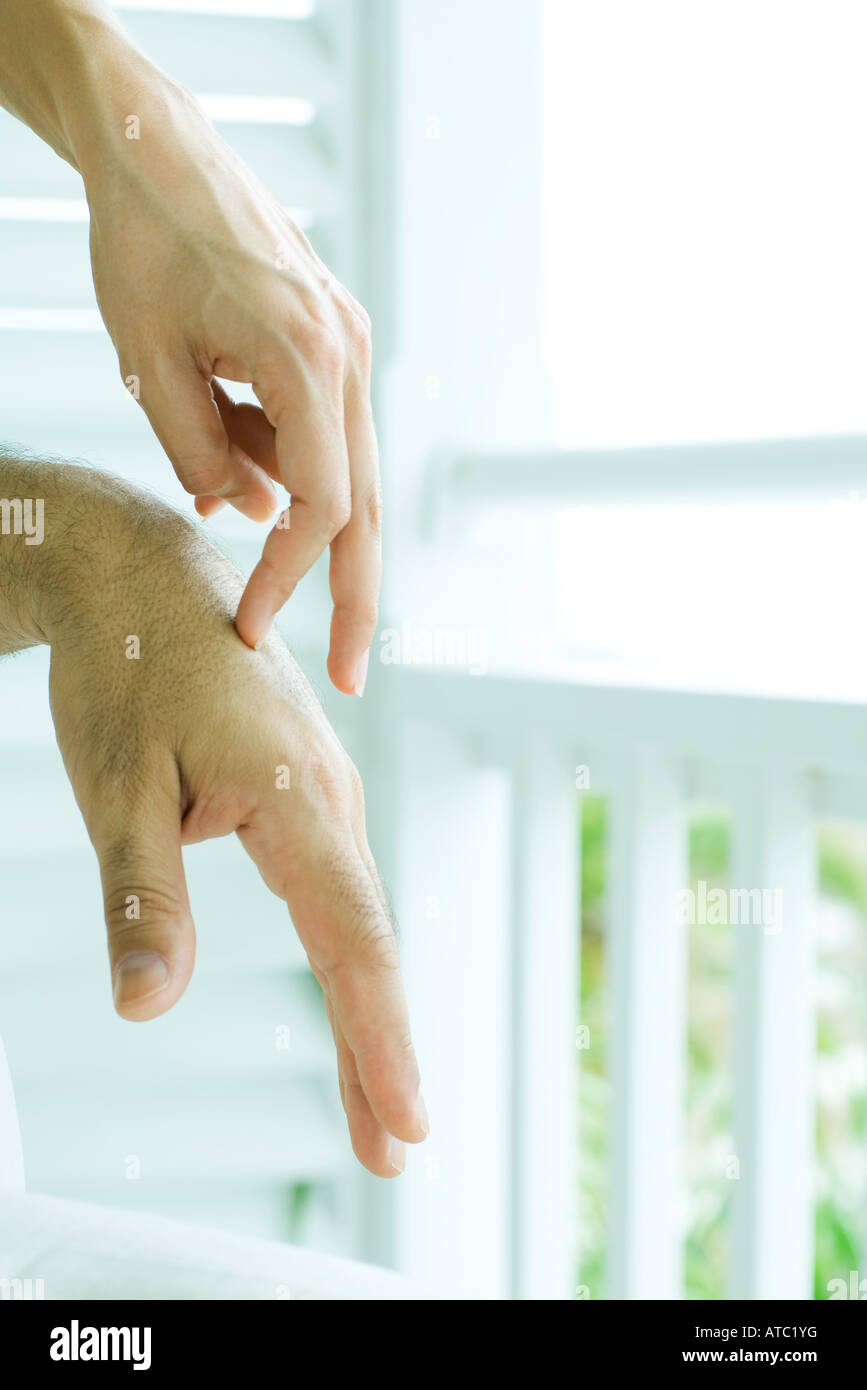 Woman touching man's hands with fingers, cropped view, close-up Stock Photo