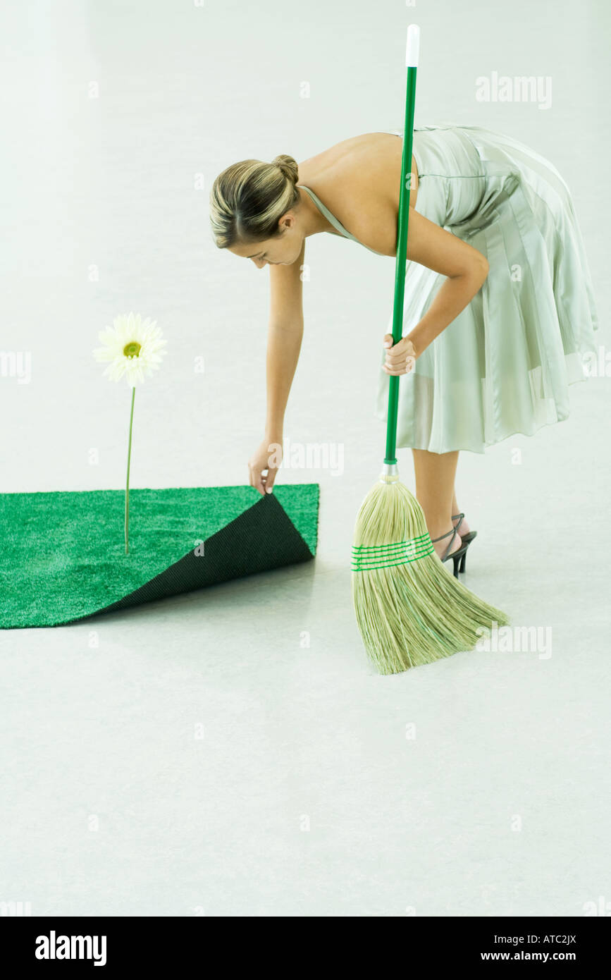 Woman sweeping under rug of artificial turf Stock Photo Alamy