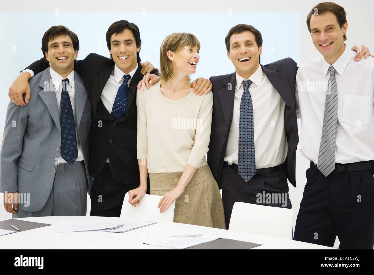 Team of business associates standing with arms around each other ...