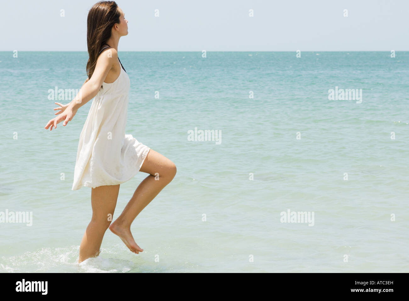 Young woman running in ocean, arms out, side view Stock Photo