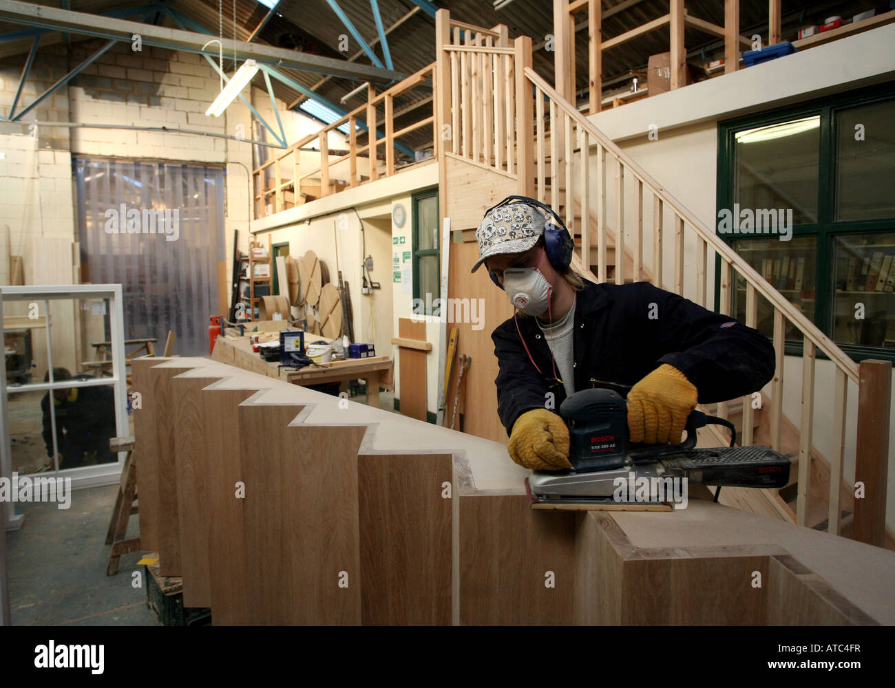 A worker sands a set of stairs at a joinery factory in Maldon