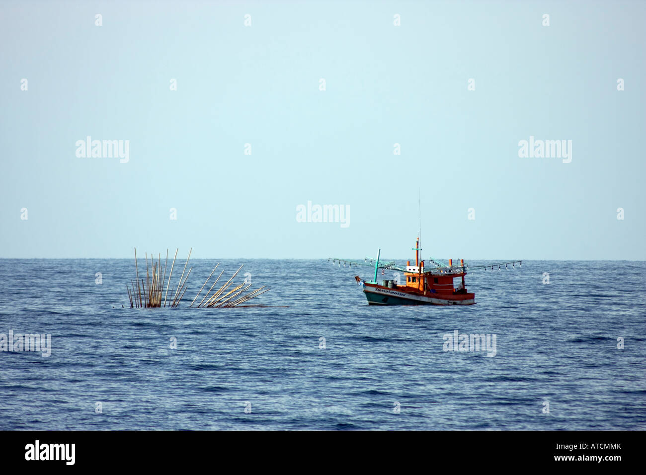 Floating bamboo bouy to mark fish traps in the Andaman sea, Thailand. A fishing vessel is moored near the trap. February 5, 20 Stock Photo