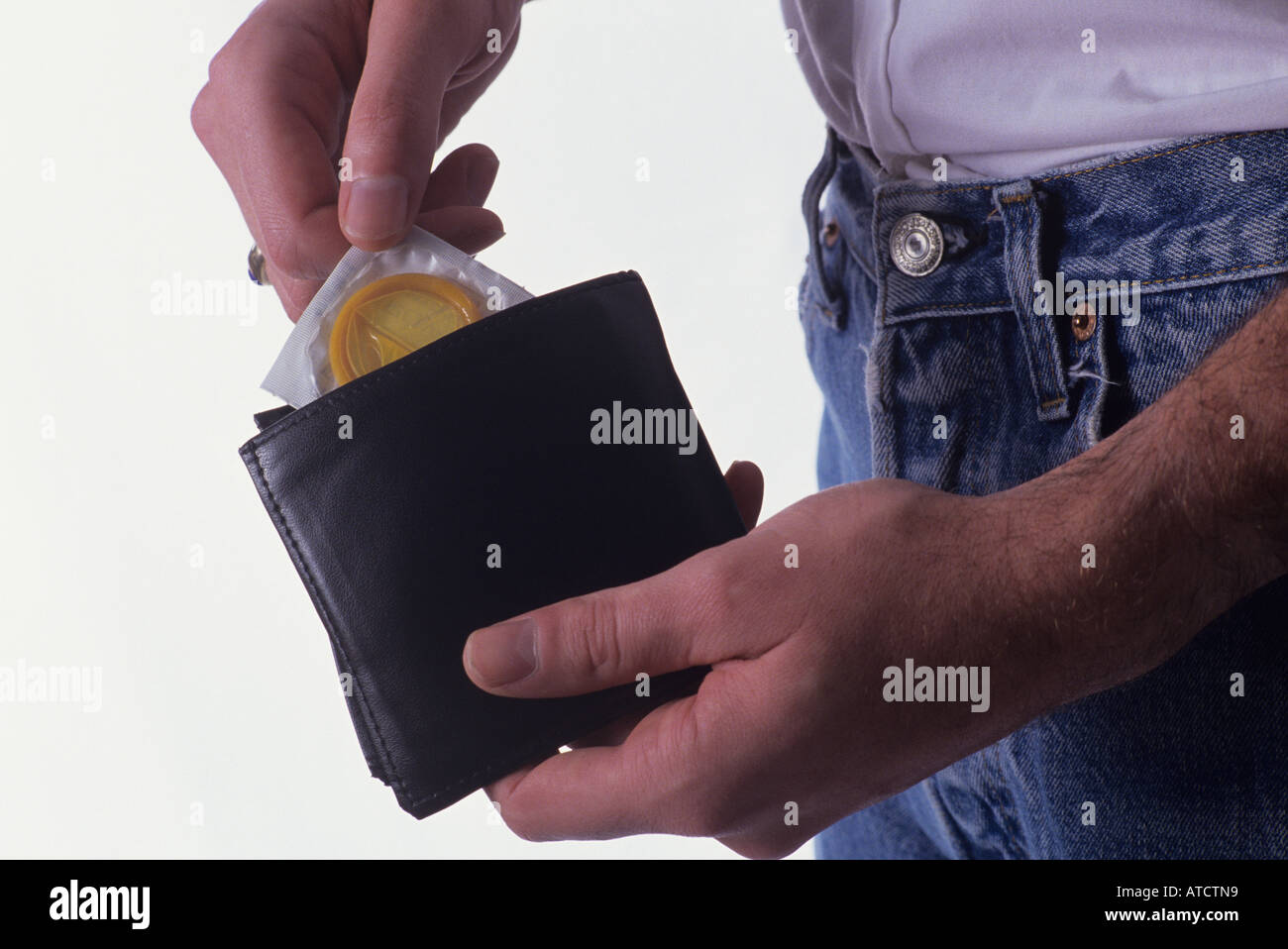 Man pulling condom out of his wallet studio set up with white