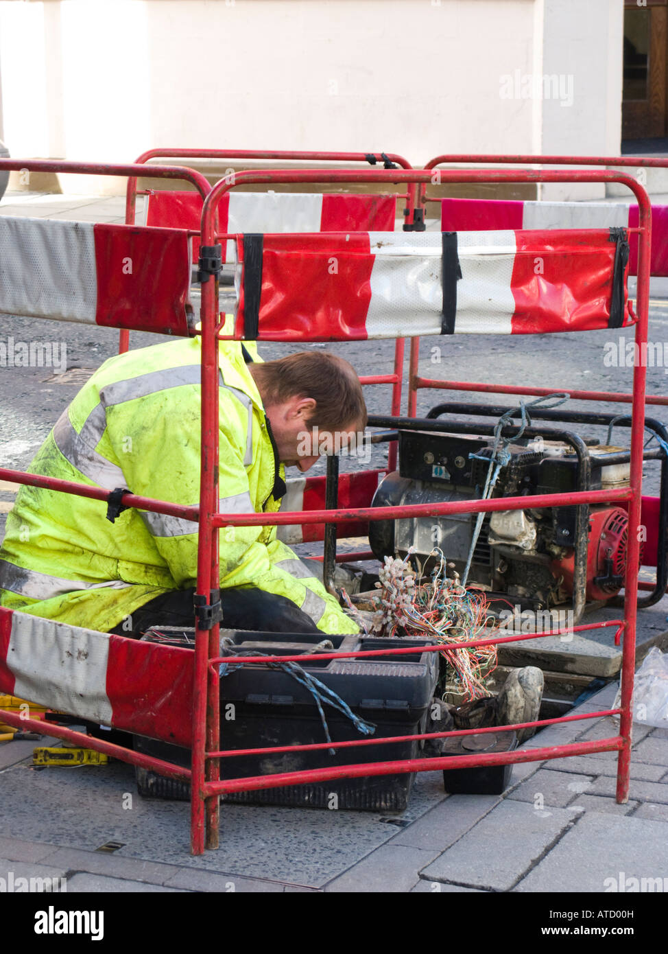 BT British enginner working fixing telephone lines down manhole