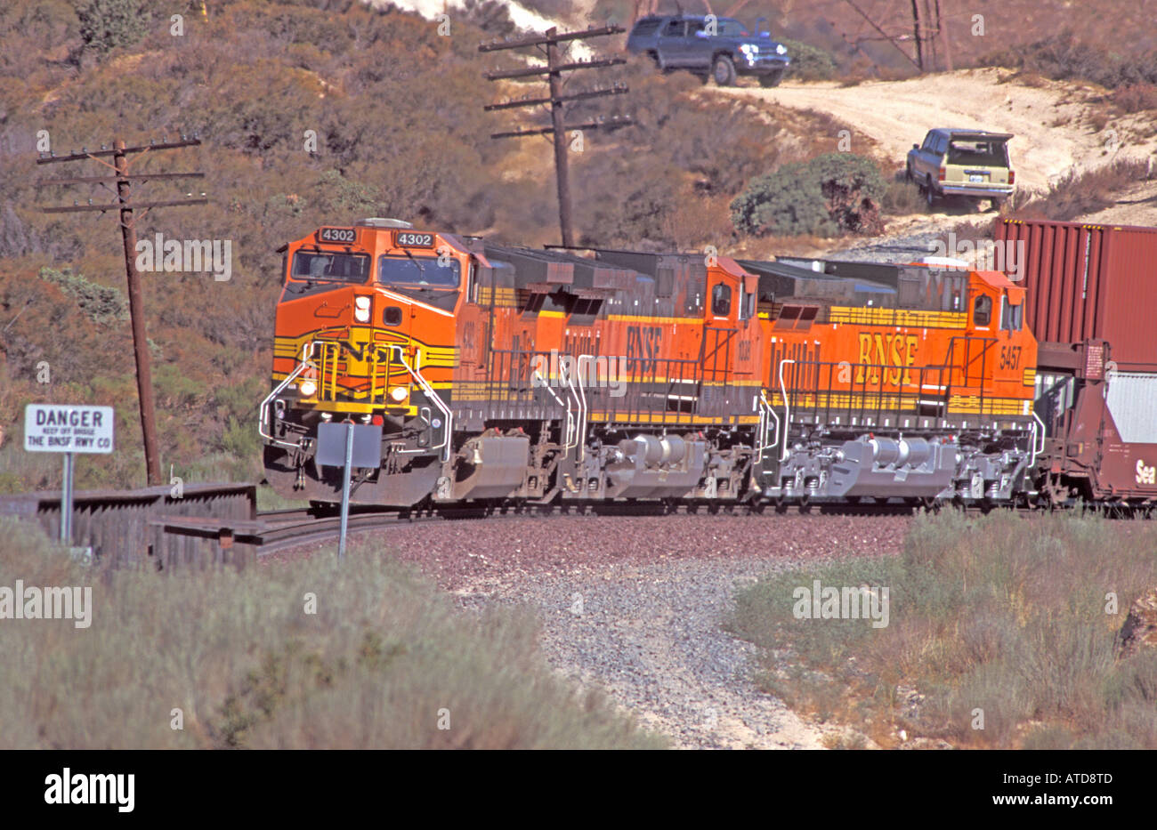 Three BNSF locomotives numbers 4302 1038 and 5457 with a train of shipping containers on the climb of the Cajon Pass Stock Photo