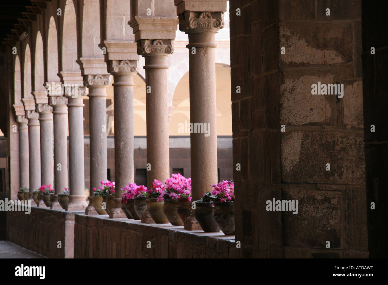 Arched columns and potted flowers line the courtyard of the Iglesia de Santo Domingo, Cusco Peru Stock Photo