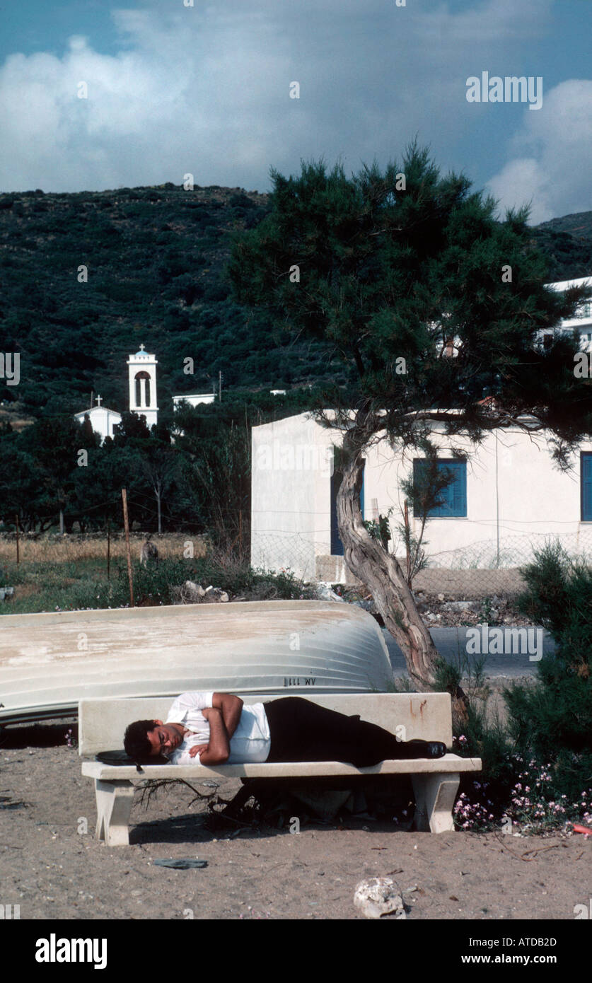 Man asleep on a bench near the beach in Greece Stock Photo