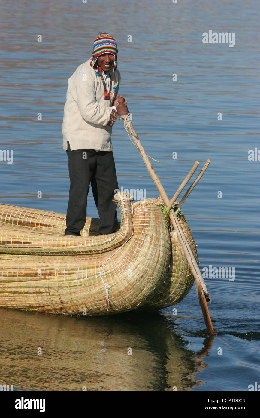 An Uros man navigates a reed boat on Lake Titicaca Peru Stock Photo