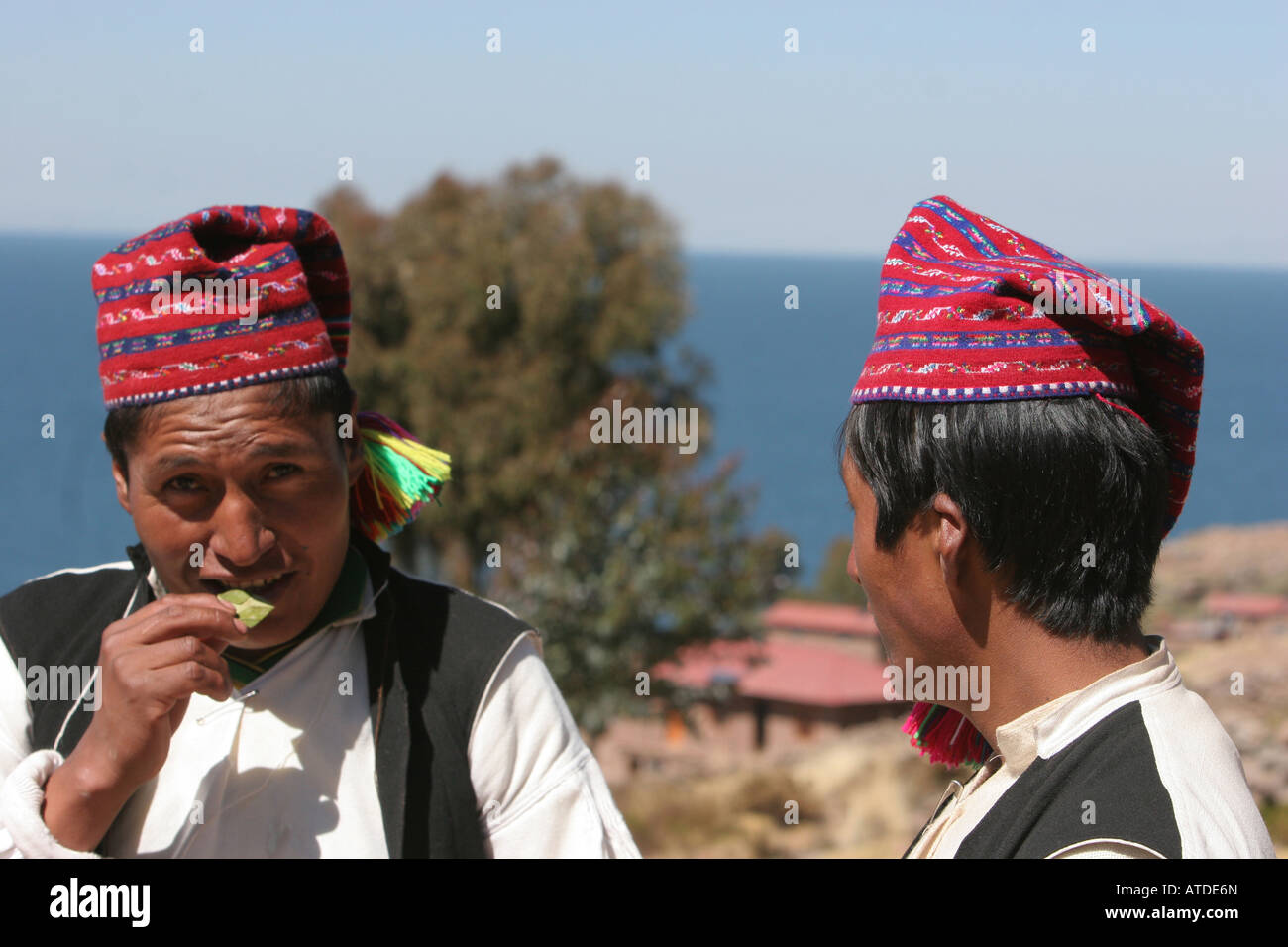 Two Peruvian men share cocoa leaves a traditional form of greeting on the island of Taquile Stock Photo