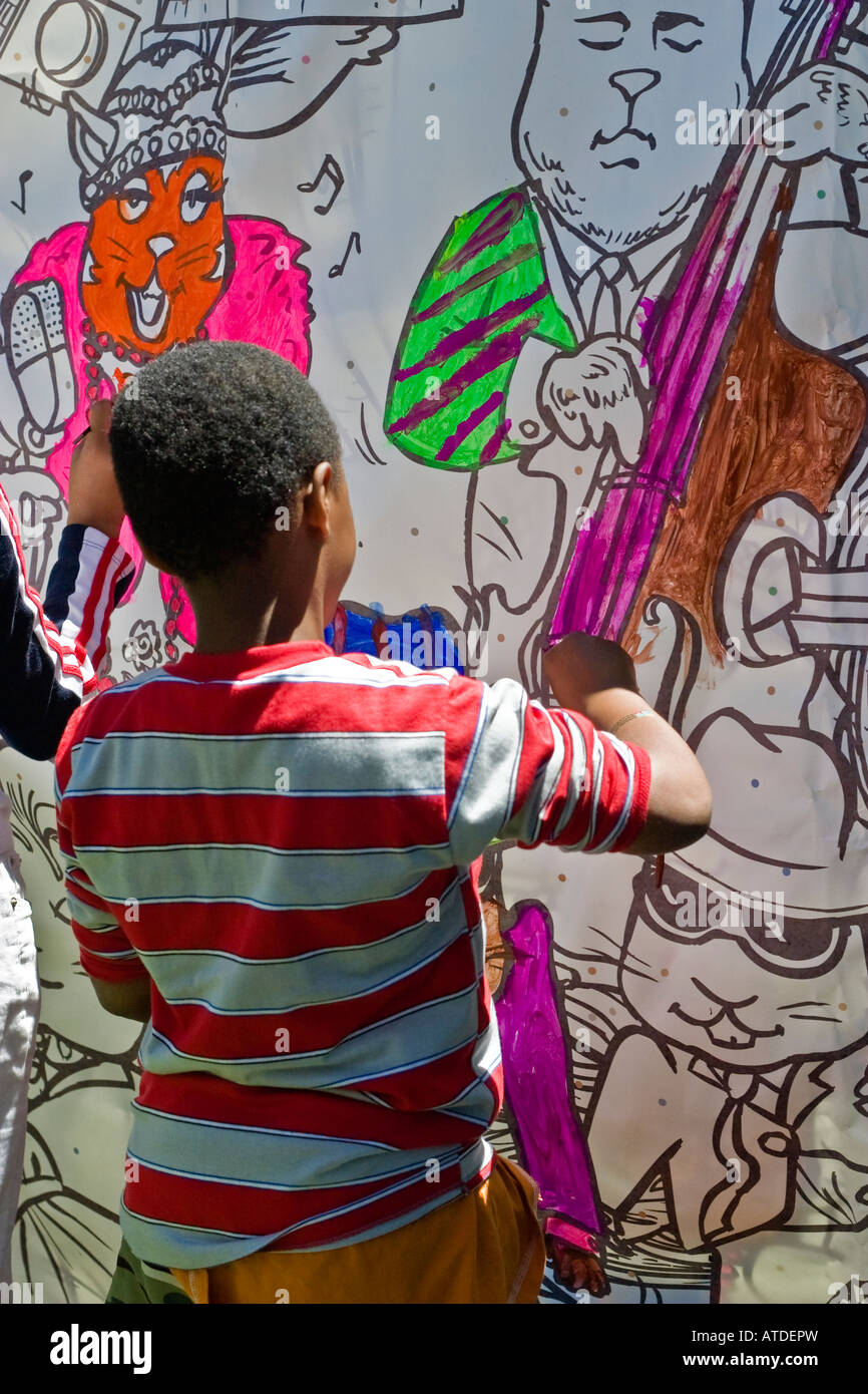 Black boy 10-12 years, painting a mural at an outdoor children's event in Toronto Canada Stock Photo