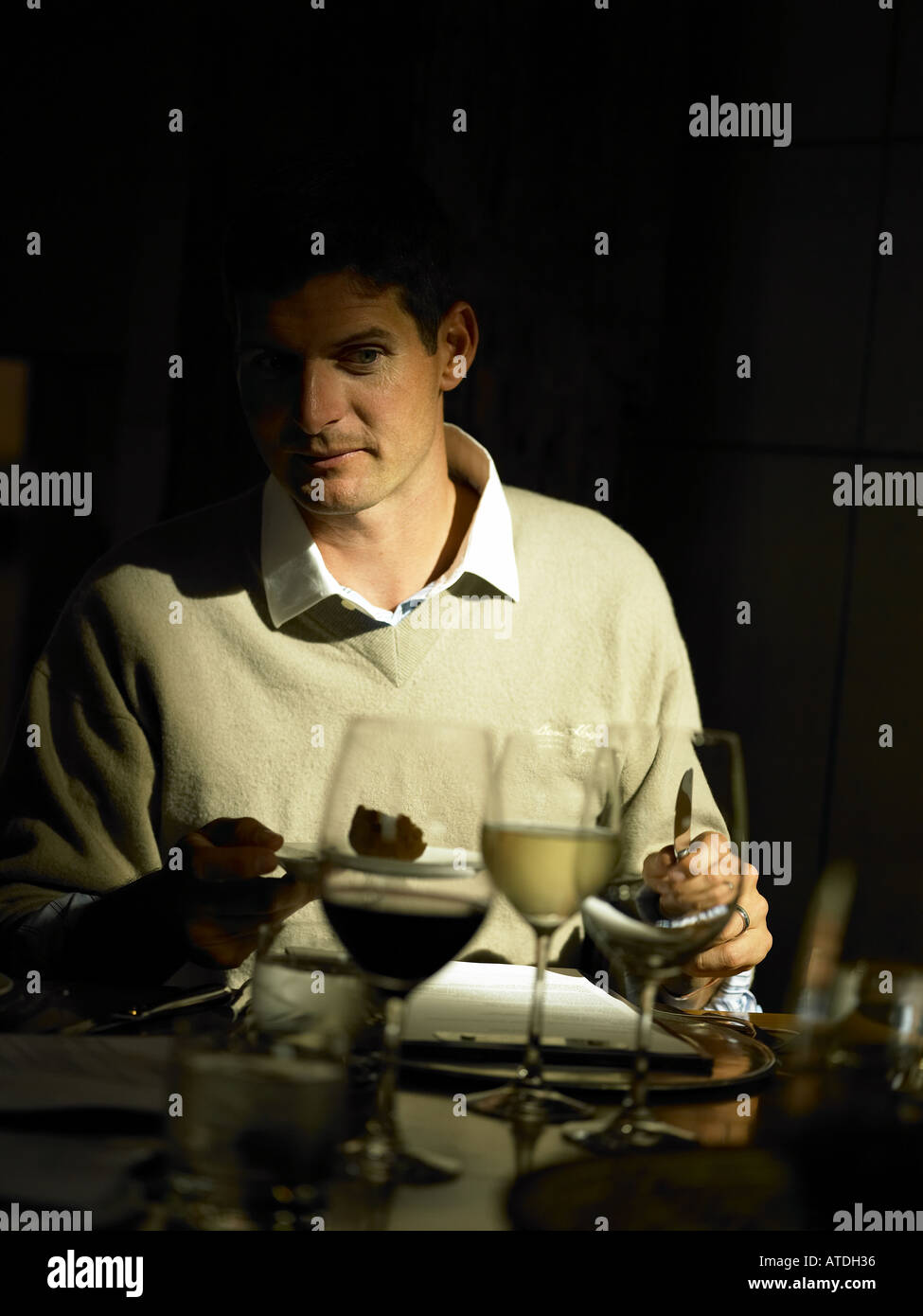 young man in jumper and shirt on his own enjoying lunch in a restaurant with wine and sunlight streaming through window and fal Stock Photo