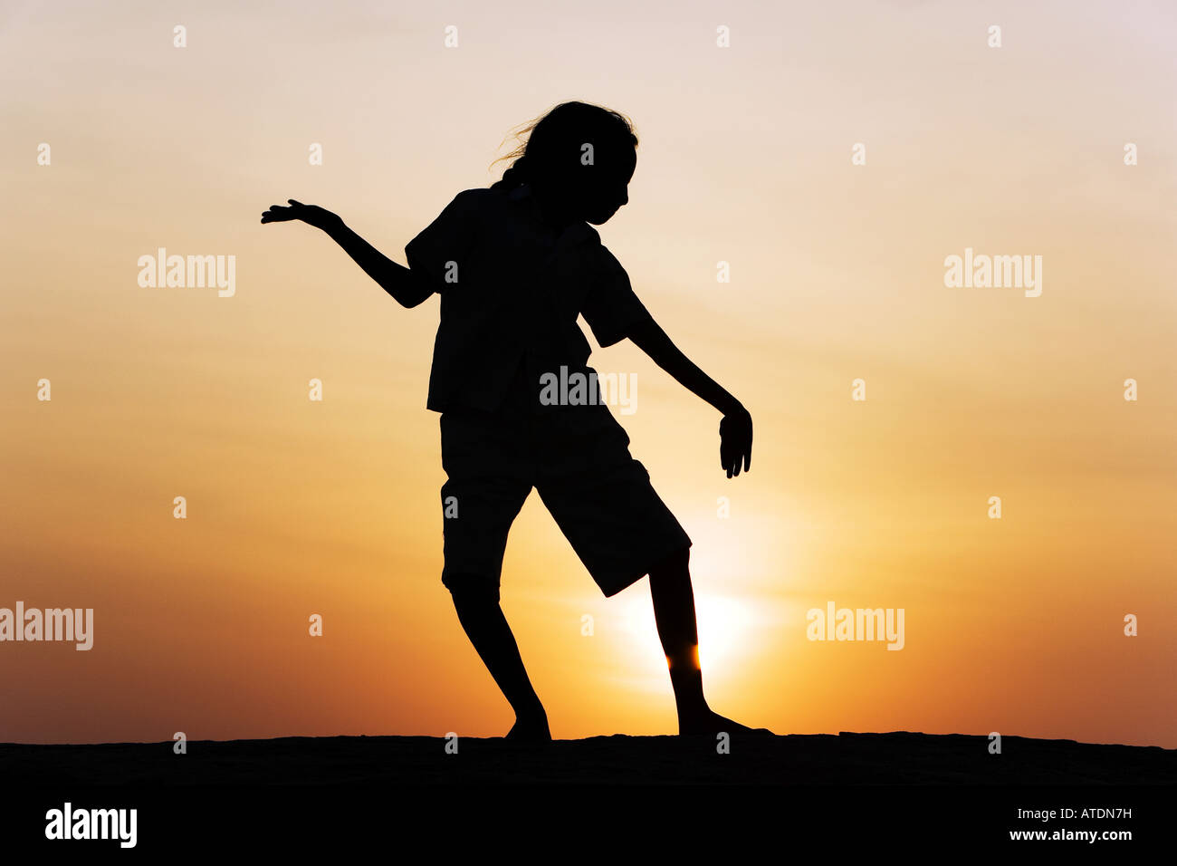 Indian girl silhouette dancing on a rock at sunset. India Stock Photo