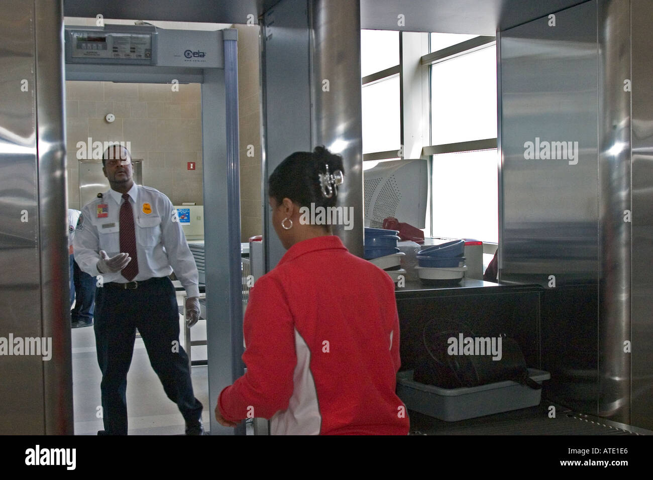 An airport security screener waves a traveller through a metal detector