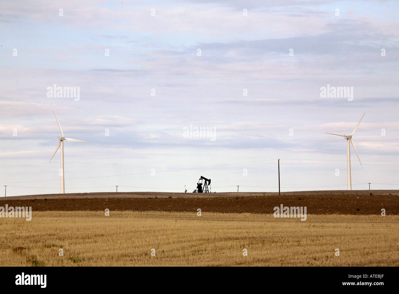 Oil pump jack between two windmill electricity generators Stock Photo