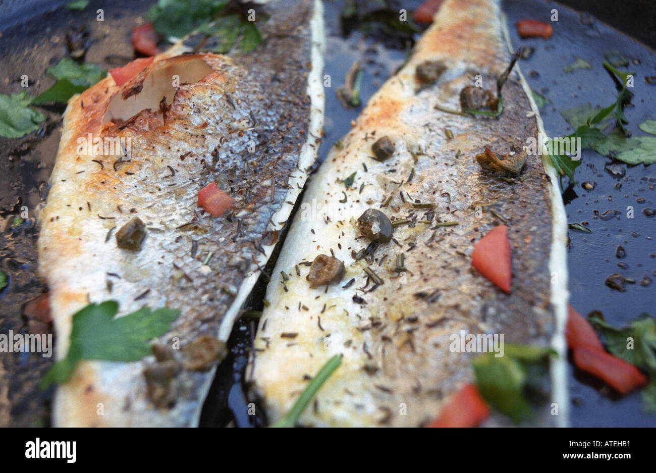 two bass fillets grilled with thyme parsley capers and tomato Stock Photo