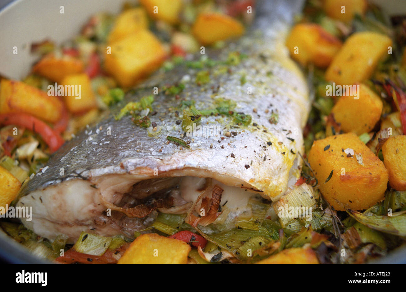 roast sea bream on a bed of leak and red pepper with safron roast potatoes Stock Photo