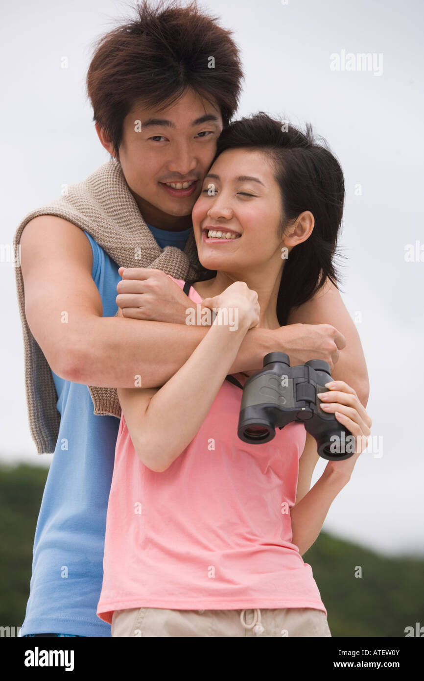 Portrait of a young man embracing a young woman from behind Stock Photo ...